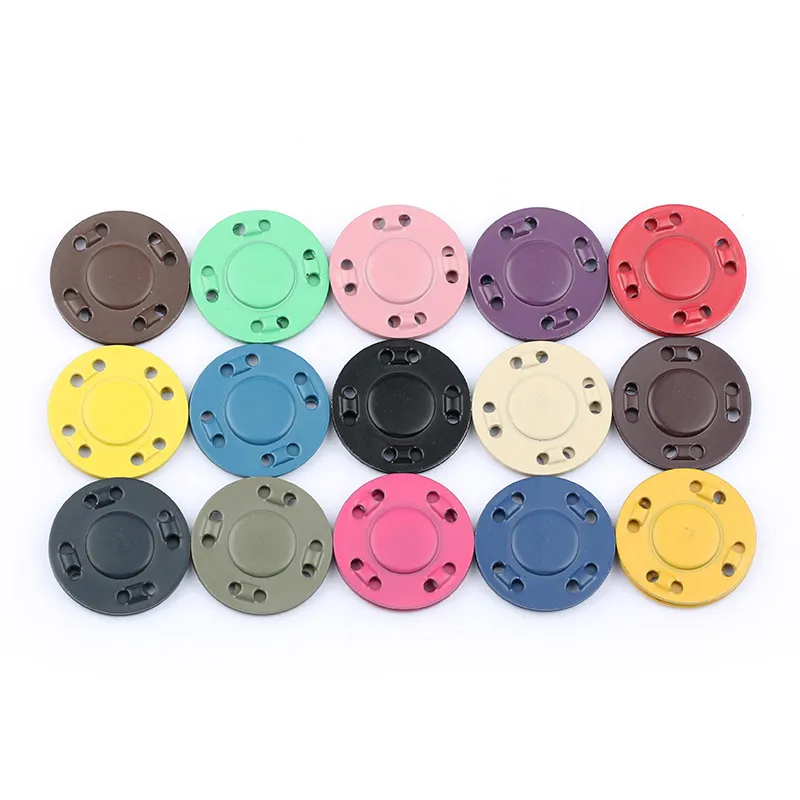 A collection of colorful round magnetic snap closures arranged in a grid pattern. These closures come in various shades, including brown, green, pink, purple, red, yellow, blue, black, beige, and gray. Each snap features four small holes around the edges, likely for secure attachment to fabric or leather materials. These magnetic closures are commonly used for bags, wallets, and other fashion accessories to provide a secure and stylish fastening mechanism.